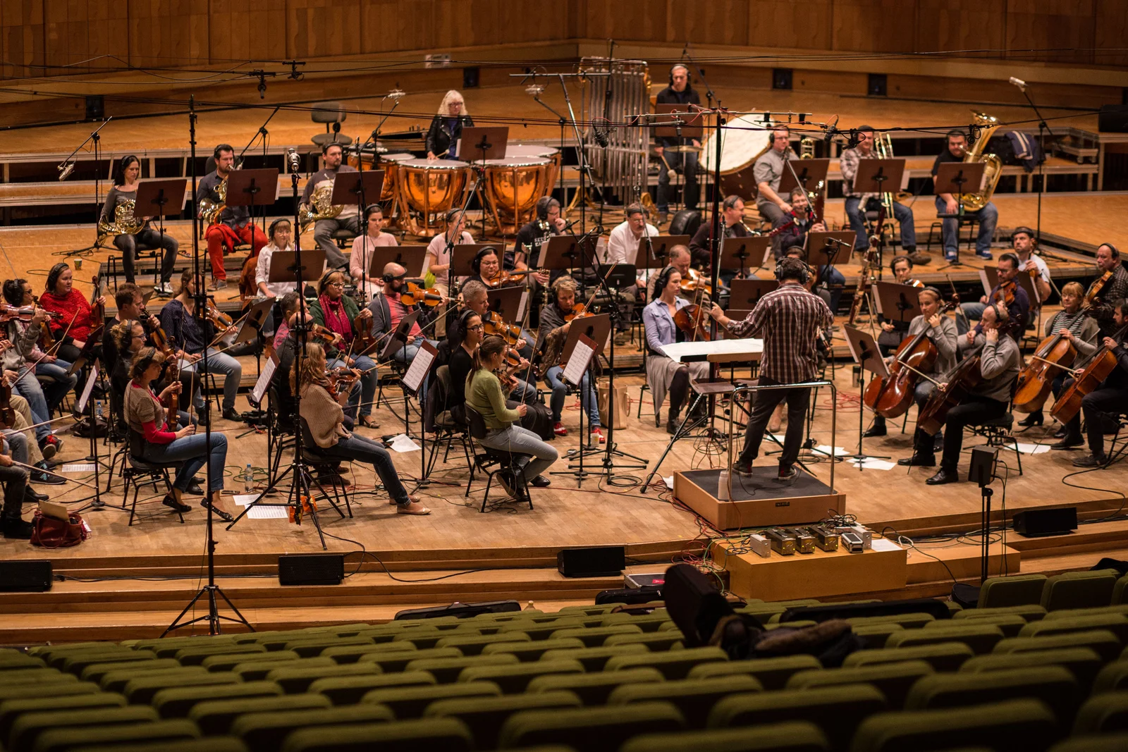 A symphony orchestra and conductor mid-session on a concert-hall stage
