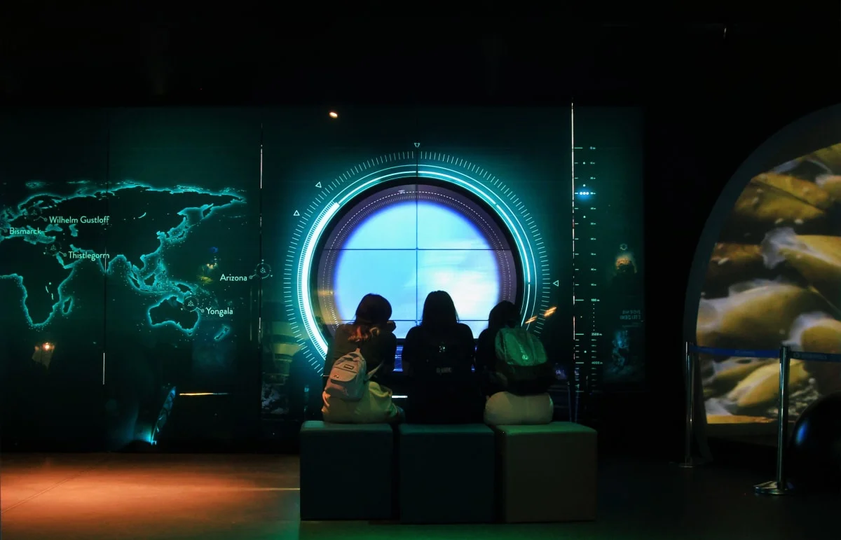 Visitors seated at a circular porthole display
