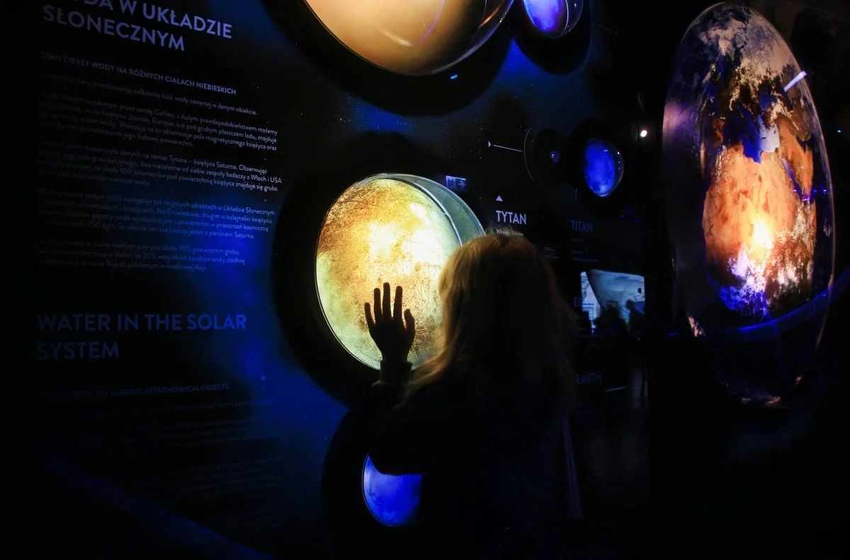 A child touching an illuminated planet in the solar-system display