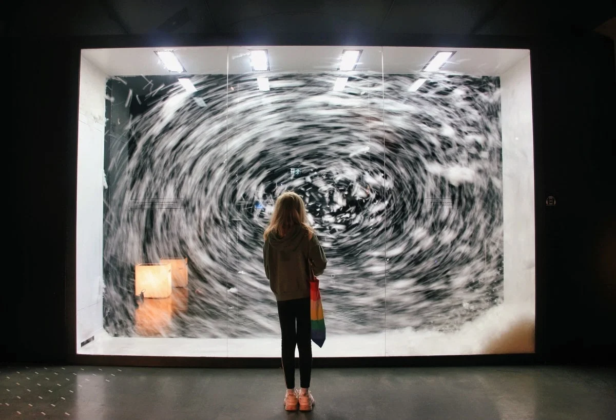 A visitor in front of a large whirlpool artwork